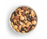 Mezcla de frutos secos Amor Portuario con pipas de calabaza, almendras blanqueadas, almendras marrones naturales, cacahuetes y macadamias en bol blanco sobre fondo blanco
